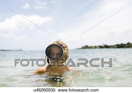 Boy (8-9) wearing swimming goggles standing in sea View Large Photo Image Stock Photography - Boy (8-9) wearing swimming goggles standing in sea. Fotosearch