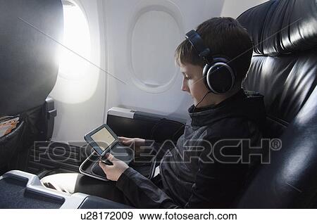 Stock Photo - Boy sitting in plane and playing video game. Fotosearch