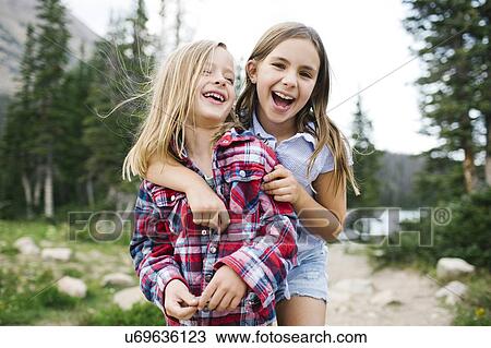 Stock Image - Brother (6-7) and sister ( 8-9) playing in forest. Fotosearch