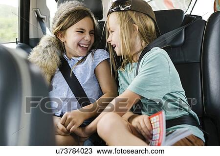 Stock Image - Brother (6-7) and sister ( 8-9) playing in car. Fotosearch