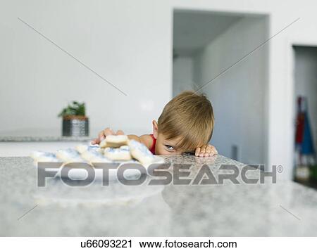 Stock Image - Brother (6-7) reaching for cookies. Fotosearch
