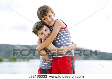 Brothers (4-5, 6-7) embracing on beach by lake View Large Photo Image Stock Image - Brothers (4-5, 6-7) embracing on beach by lake. Fotosearch