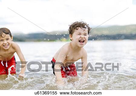 Stock Photography - Brothers (4-5, 6-7) splashing water in lake. Fotosearch