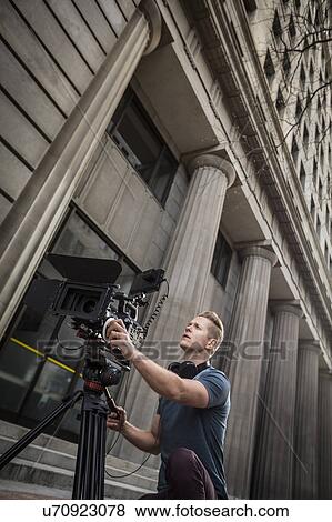 Stock Photo - Camera operator filming in front of building. Fotosearch