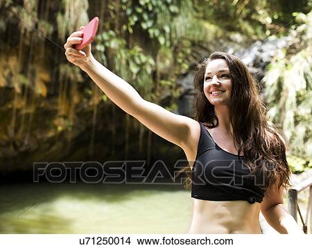 Picture - Caribbean Islands, Saint Lucia, woman taking selfie by waterfall. Fotosearch