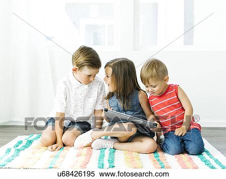 Children (2-3, 6-7) sitting on rug with digital tablet View Large Photo Image Stock Photography - Children (2-3, 6-7) sitting on rug with digital tablet. Fotosearch