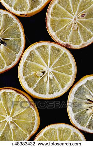 Stock Image - Close up of dried lemon slices on black background. Fotosearch