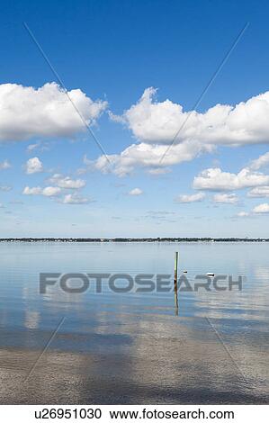 Stock Image - Clouds reflecting in water on sunny day. Fotosearch