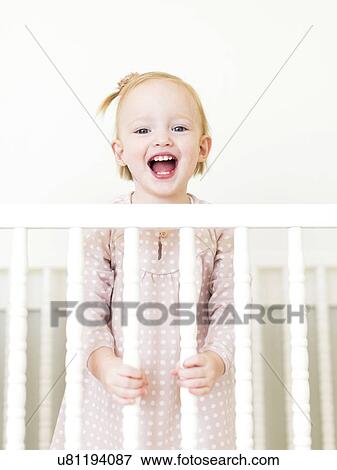 Content small girl ( 12-17 months) with mouth open standing in crib View Large Photo Image Stock Photo - Content small girl ( 12-17 months) with mouth open standing in crib. Fotosearch