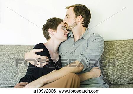 Stock Photograph - Couple embracing and kissing on sofa. Fotosearch