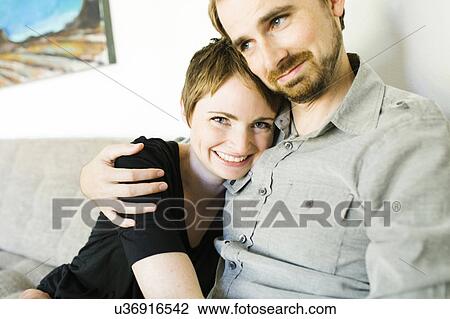 Stock Image - Couple sitting on sofa. Fotosearch