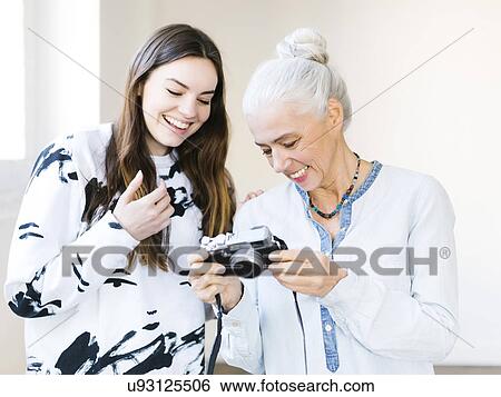 Stock Photograph - Daughter and mother preparing to make photographs. Fotosearch