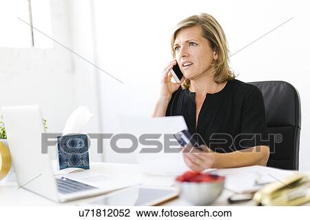 Stock Image - Displeased Mature woman paying bills. Fotosearch