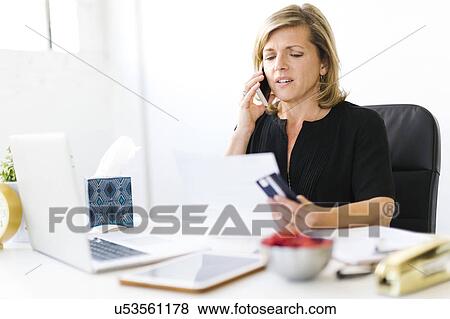 Stock Photo - Displeased Mature woman paying bills. Fotosearch