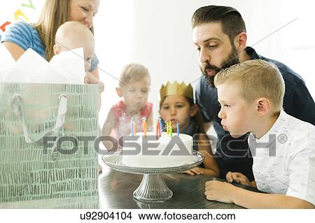 Family with four children (6-11 months, 2-3, 6-7) blowing candles on birthday cake View Large Photo Image Picture - Family with four children (6-11 months, 2-3, 6-7) blowing candles on birthday cake. Fotosearch