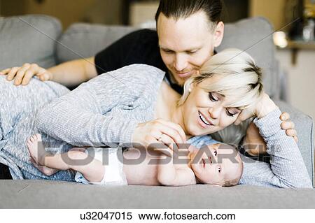 Stock Photography - Family with one day son (0-1 months) lying on sofa. Fotosearch