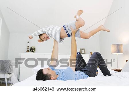 Stock Image - Father and son (4-5) playing in bedroom. Fotosearch