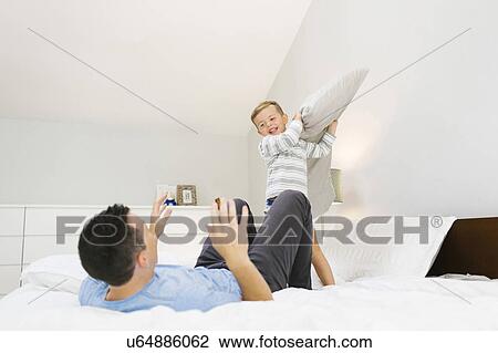 Stock Image - Father and son (4-5) playing in bedroom. Fotosearch