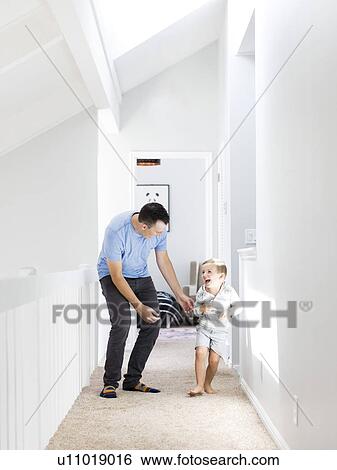 Stock Photograph - Father and son (4-5) playing in corridor. Fotosearch