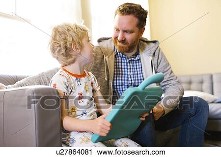 Stock Image - Father and son (4-5) playing with electronic toy. Fotosearch