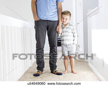 Stock Image - Father and son (4-5) standing in corridor. Fotosearch