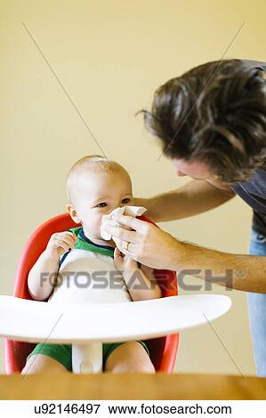 Stock Photo - Father assisting son (12-17 months) to blow nose. Fotosearch