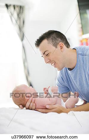 Stock Photo - Father carrying daughter (0-1 months). Fotosearch