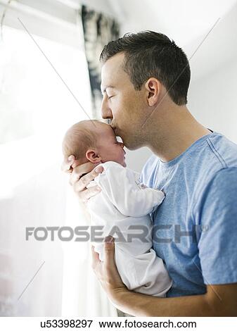 Father carrying daughter (0-1 months) and kissing View Large Photo Image Stock Photo - Father carrying daughter (0-1 months) and kissing. Fotosearch