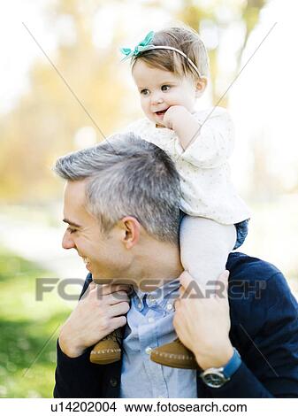 Picture - Father carrying daughter (12-17 months) on shoulders. Fotosearch