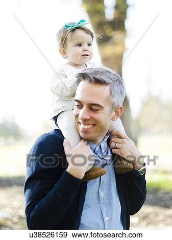 Stock Photo - Father carrying daughter (12-17 months) on shoulders. Fotosearch