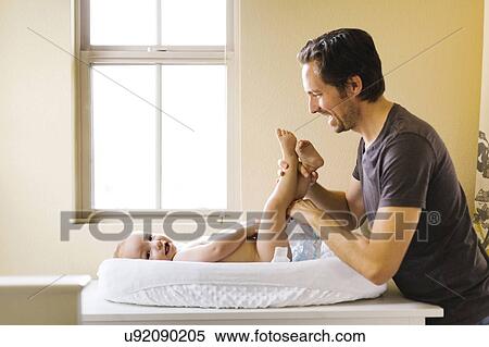 Father changing son's (12-17 months) diaper View Large Photo Image Stock Photography - Father changing son's (12-17 months) diaper. Fotosearch