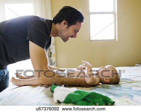 Father dressing son (12-17 months) in bedroom View Large Photo Image Stock Image - Father dressing son (12-17 months) in bedroom. Fotosearch