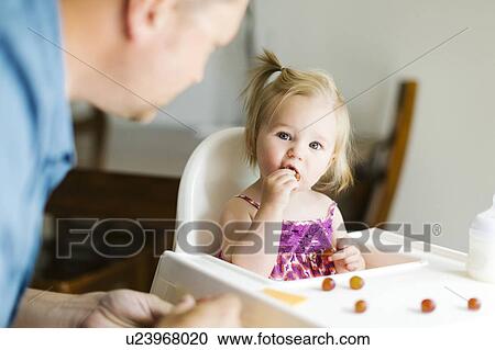 Stock Image - Father feeding baby girl (12-17 months). Fotosearch