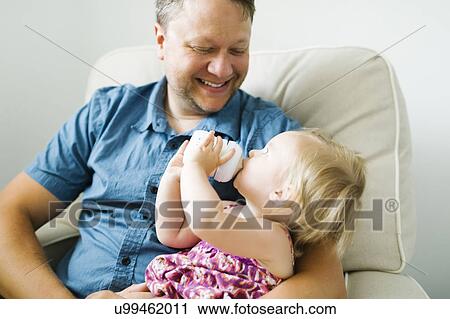 Father feeding baby girl (12-17 months) in living room View Large Photo Image Stock Image - Father feeding baby girl (12-17 months) in living room. Fotosearch