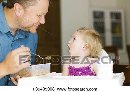 Father feeding baby girl (12-17 months) View Large Photo Image Stock Photo - Father feeding baby girl (12-17 months). Fotosearch