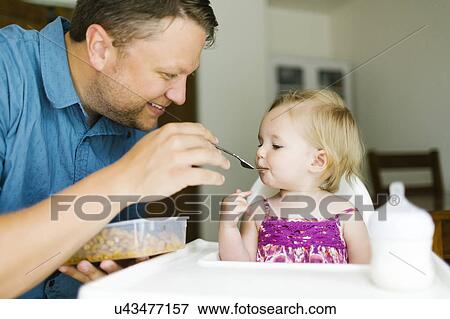 Stock Photo - Father feeding baby girl (12-17 months). Fotosearch