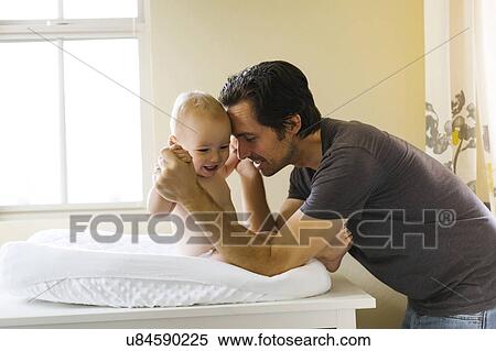 Father playing with baby boy (12-17 months) on changing mat View Large Photo Image Stock Photography - Father playing with baby boy (12-17 months) on changing mat. Fotosearch