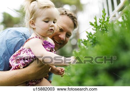 Stock Image - Father playing with baby girl (12-17 months) in backyard. Fotosearch