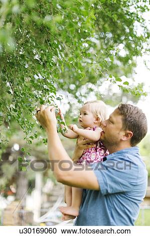 Stock Image - Father playing with baby girl (12-17 months) in backyard. Fotosearch