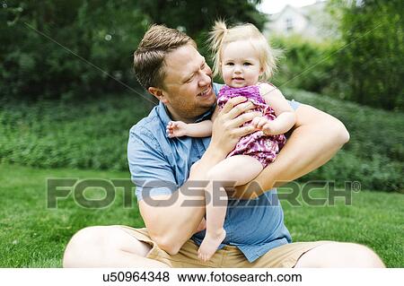 Stock Photo - Father playing with baby girl (12-17 months) in backyard. Fotosearch