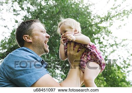 Stock Photo - Father playing with baby girl (12-17 months) in backyard. Fotosearch