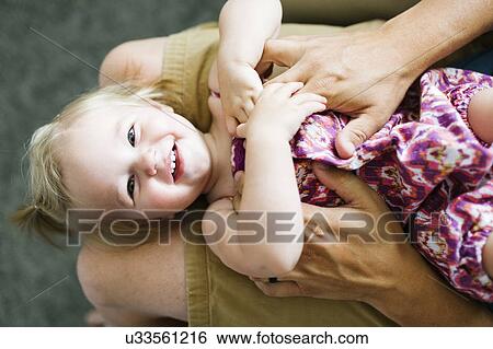 Stock Photograph - Father playing with baby girl (12-17 months). Fotosearch