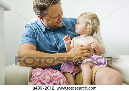 Father with baby girl (12-17 months) sitting in living room View Large Photo Image Stock Image - Father with baby girl (12-17 months) sitting in living room. Fotosearch