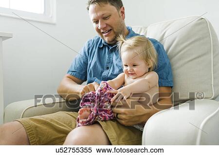 Father with baby girl (12-17 months) sitting in living room View Large Photo Image Stock Photography - Father with baby girl (12-17 months) sitting in living room. Fotosearch