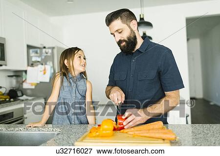 Stock Photo - Father with daughter (6-7) cooking together. Fotosearch