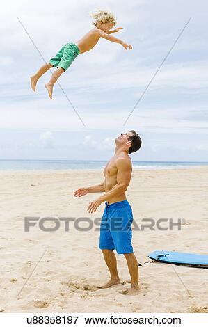 Stock Photo - Father with son (4-5) playing at beach. Fotosearch