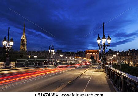 Picture - France, Nouvelle-Aquitaine, Bordeaux, Cailhau Gate, Incidental people and cars in long exposure. Fotosearch