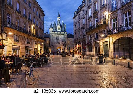Stock Photography - France, Nouvelle-Aquitaine, Bordeaux, Crowded sidewalk cafe with Cailhau Gate in background. Fotosearch