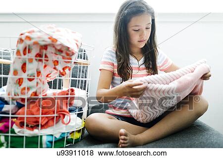 Stock Photo - Girl (10-11) folding laundry. Fotosearch