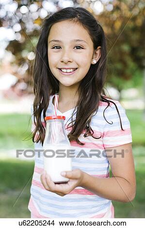 Picture - Girl (10-11) in park holding glass of milk with straw. Fotosearch